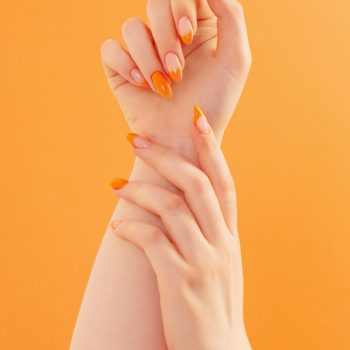 female-hand-with-manicure-orange-background